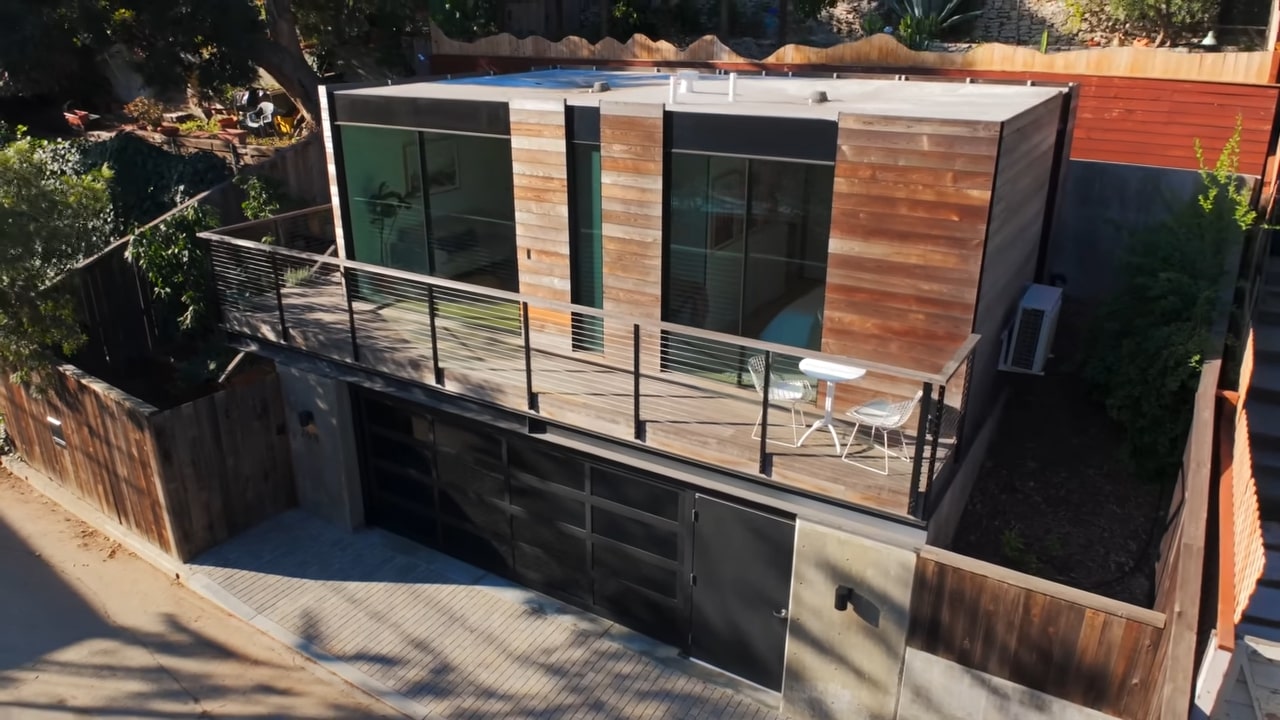 Two story tiny home with wooden exterior, glass panels and garage