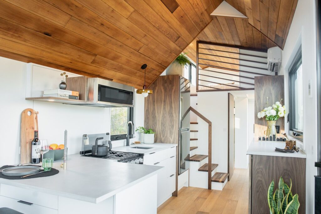 White L-shaped kitchen in tiny house with tons of storage and a huge counter