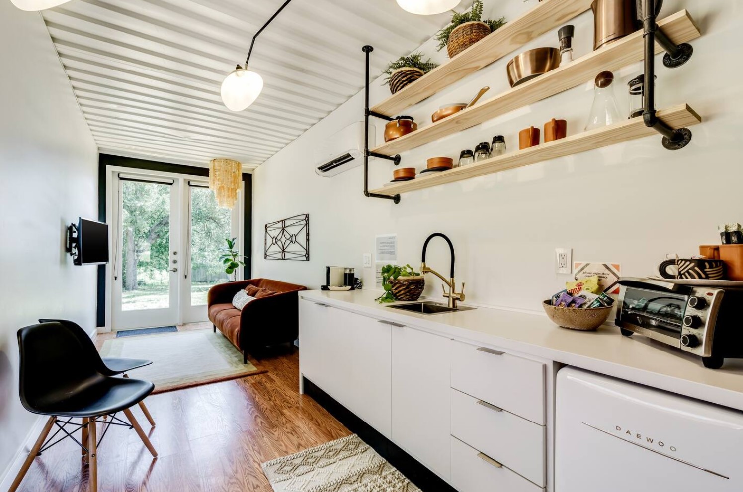 White kitchen in container home with industrial style open shelving