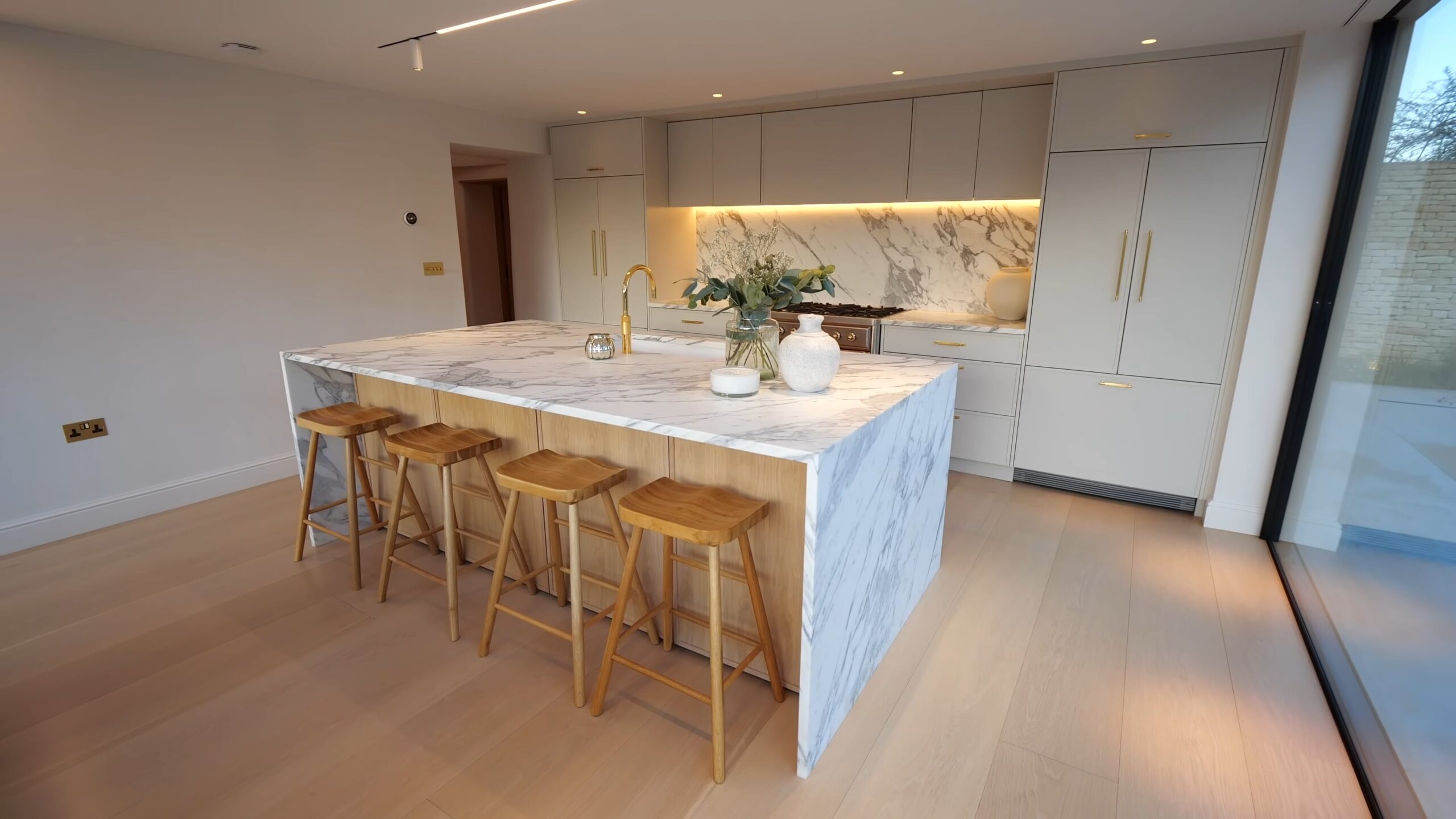 White kitchen with marble island, wooden stools and white cabinets