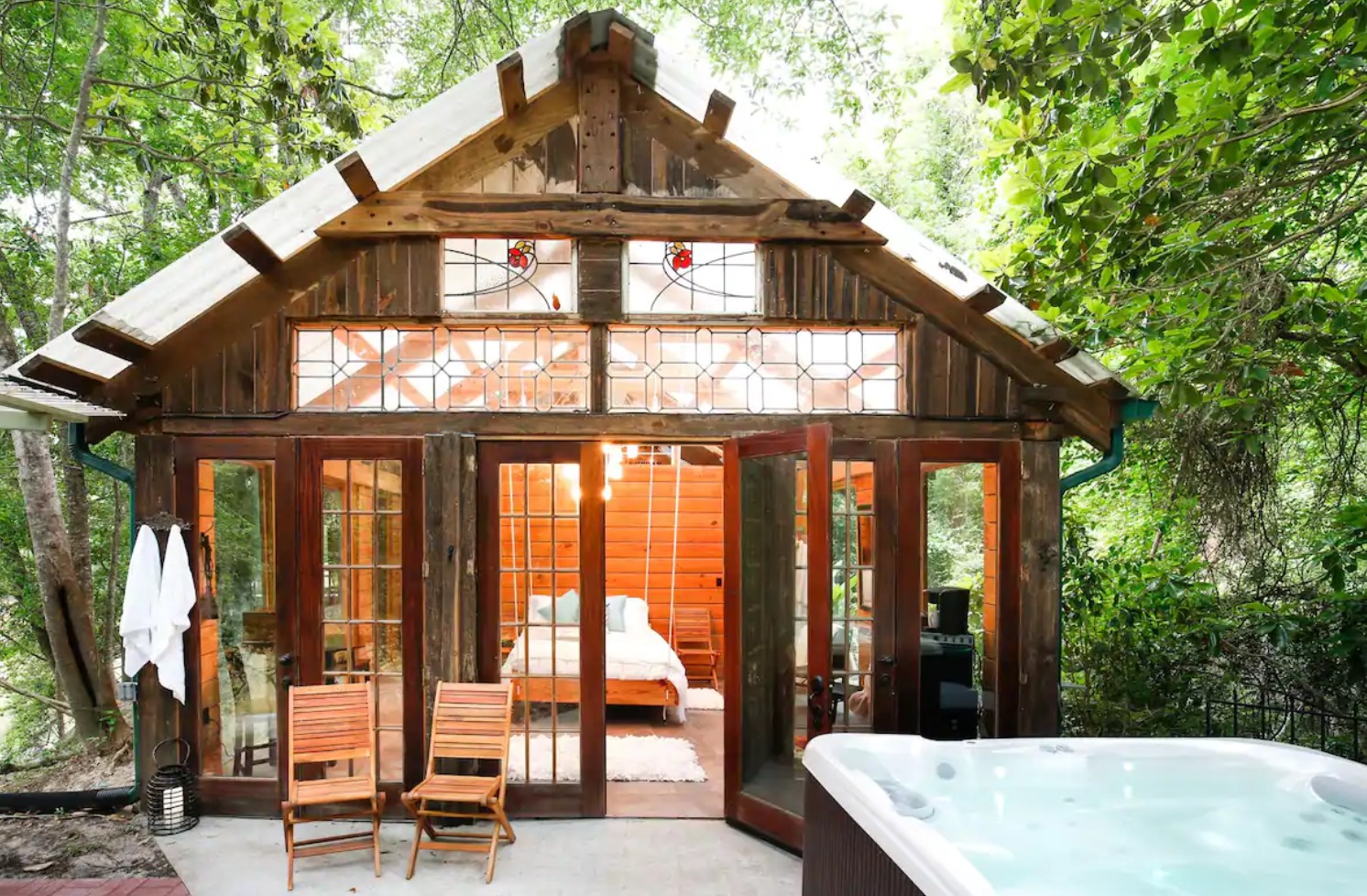 Romantic wooden cabin with a lot of windows and a swing bed