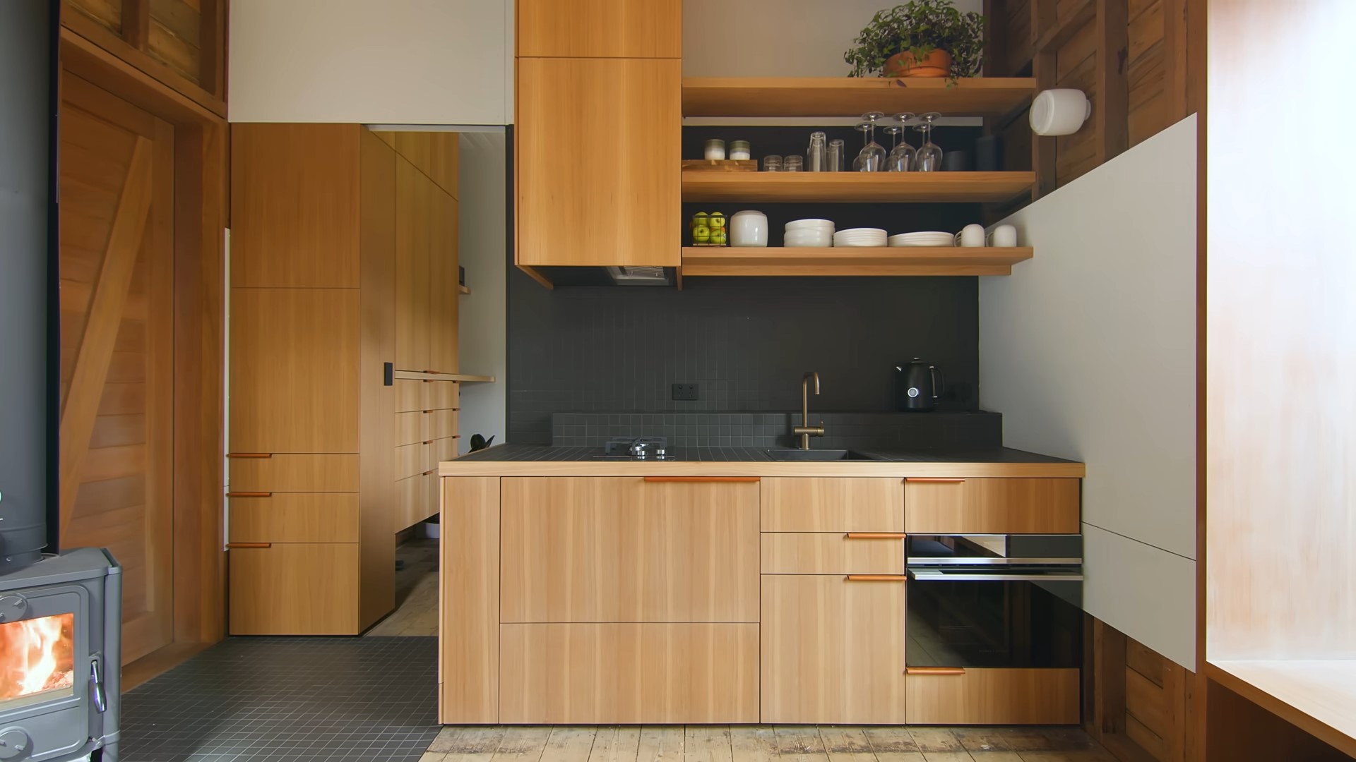 Wooden kitchen with open shelving and black tiles