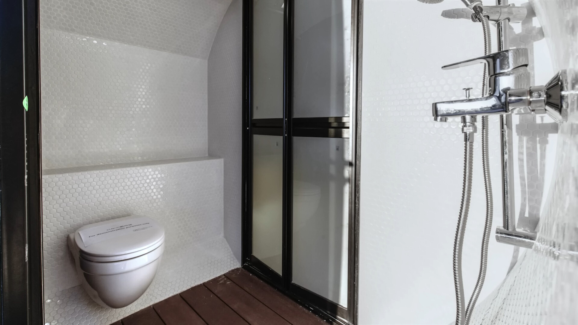 tiny bathroom with white tiles, white toilet and a shower