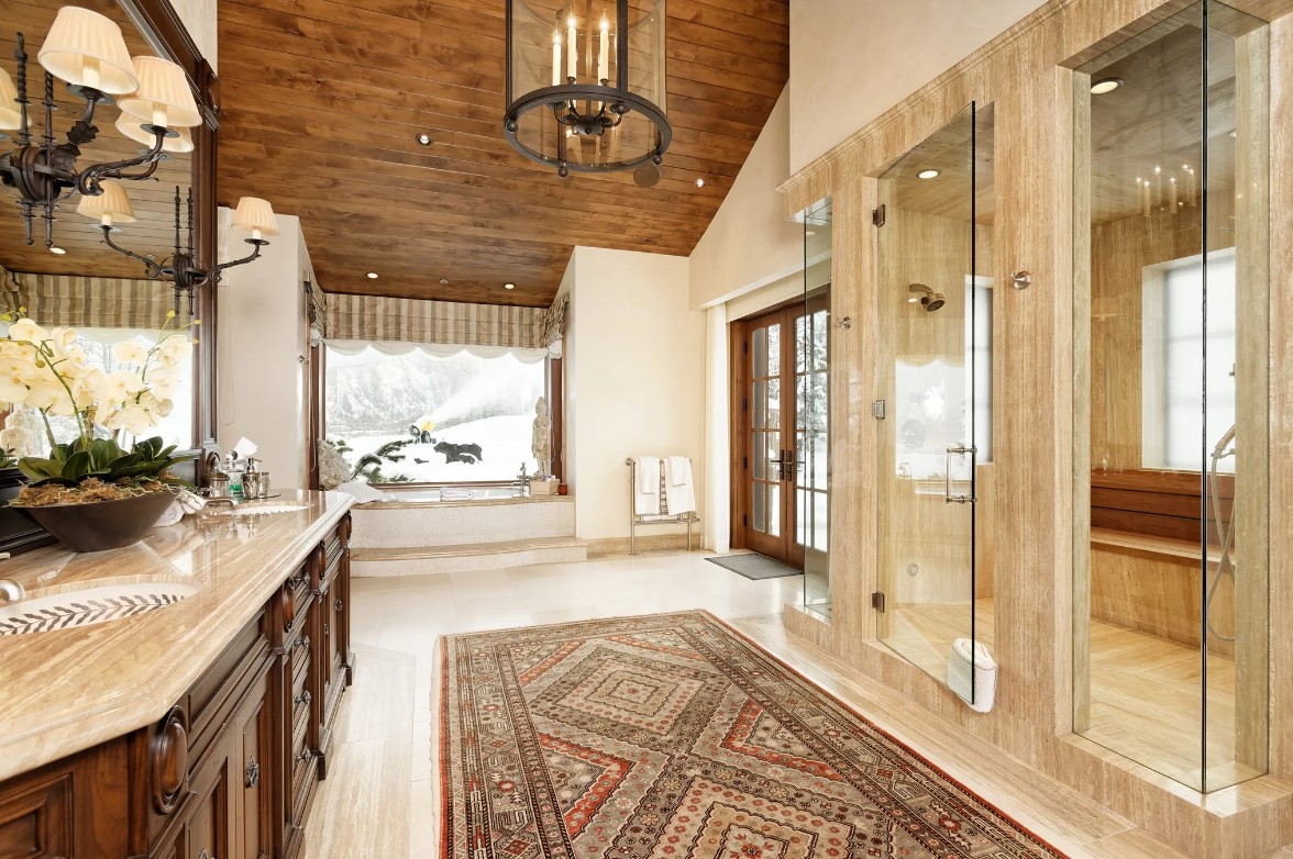 bathroom with a big shower with glass door, bath tub next to a window and a candle chandelier