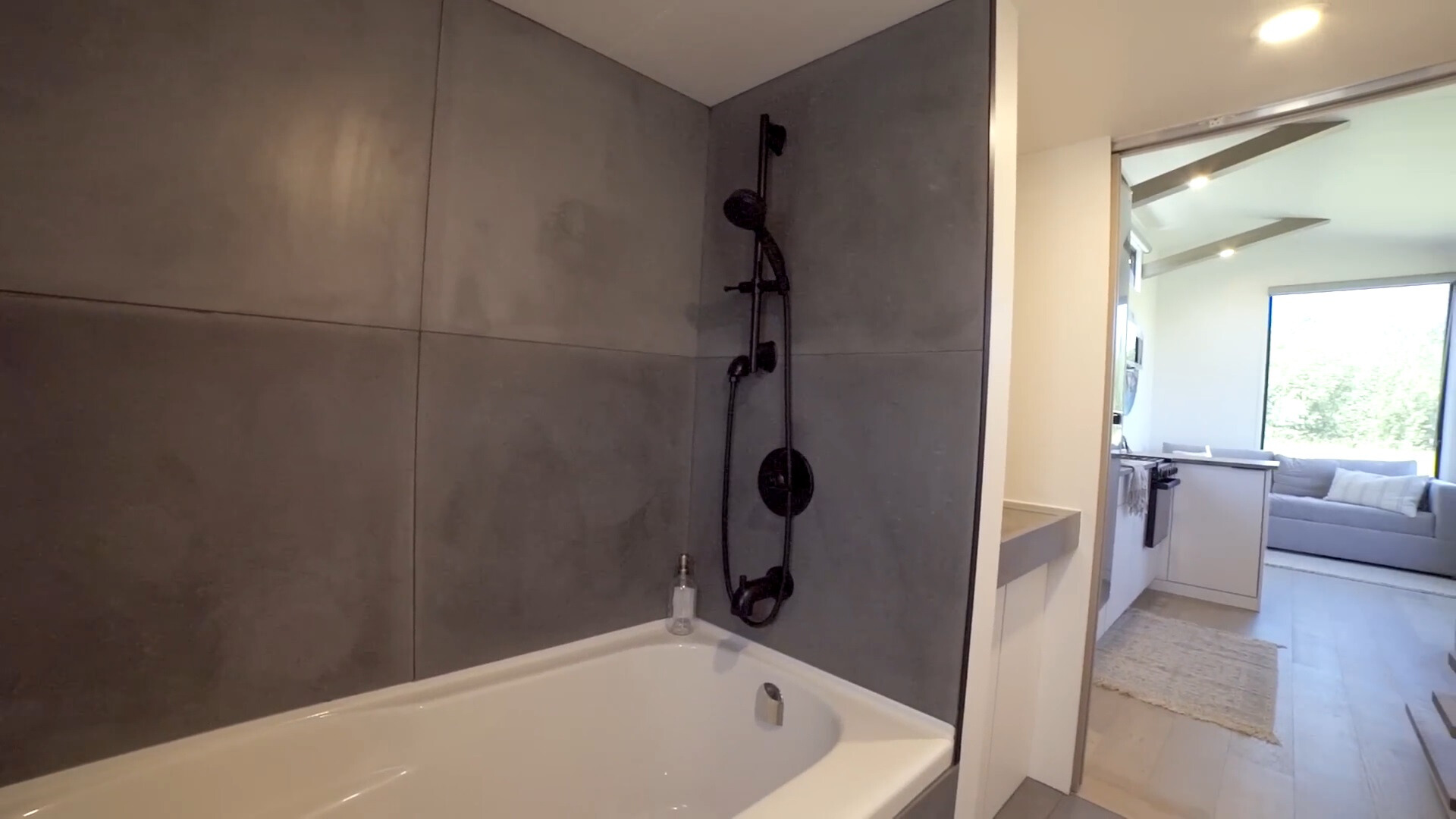 bathroom with dark gray tiles and white bathtub