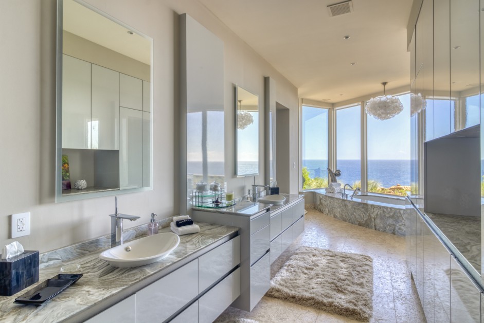 bathroom with two white sinks, two mirrors bathtub next to a window