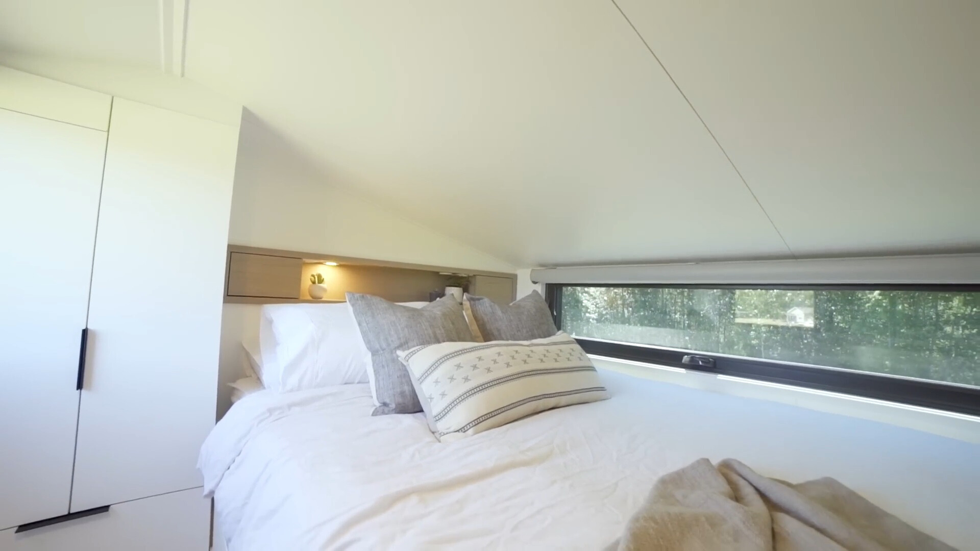 loft bedroom with a queen sized bed, white closet and a window