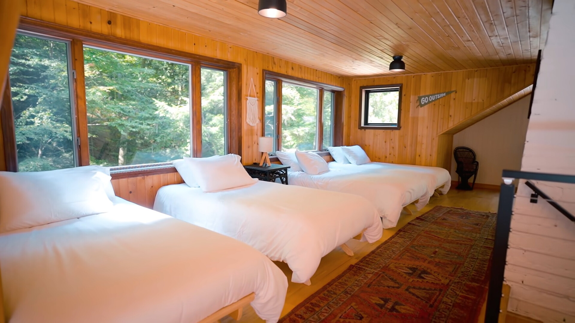 bedroom with wooden walls and a lot of beds next to each other and windows