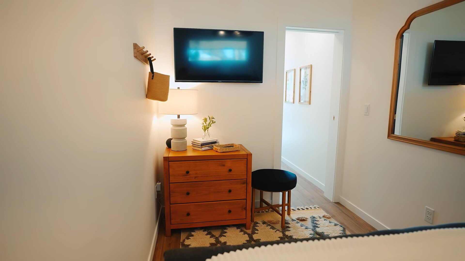 bedroom with a mirror, a flat screen tv, brown cabinet and a small black chair