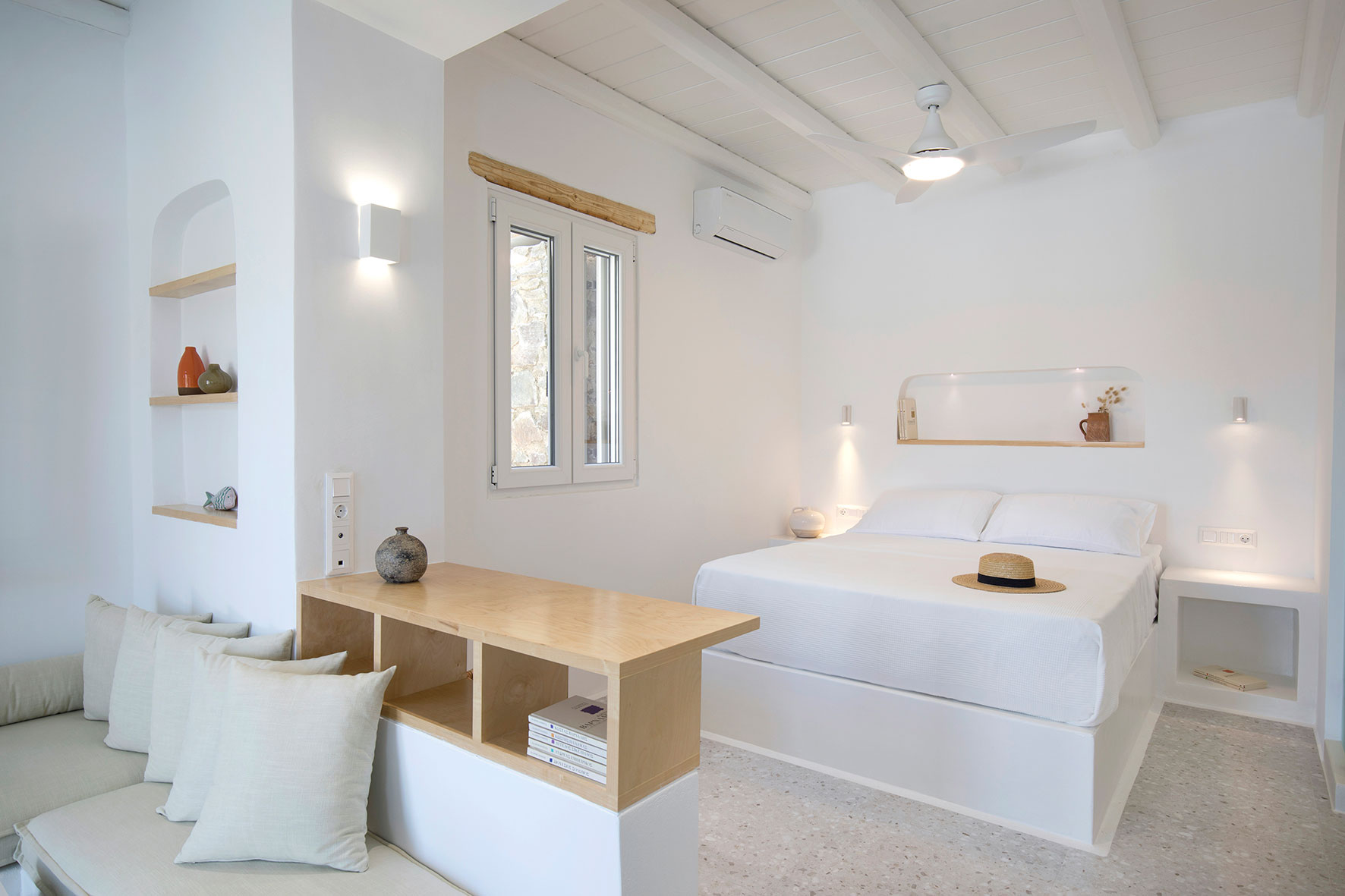 bedroom with a white bed, white bedside tables, white ceiling fan and a window