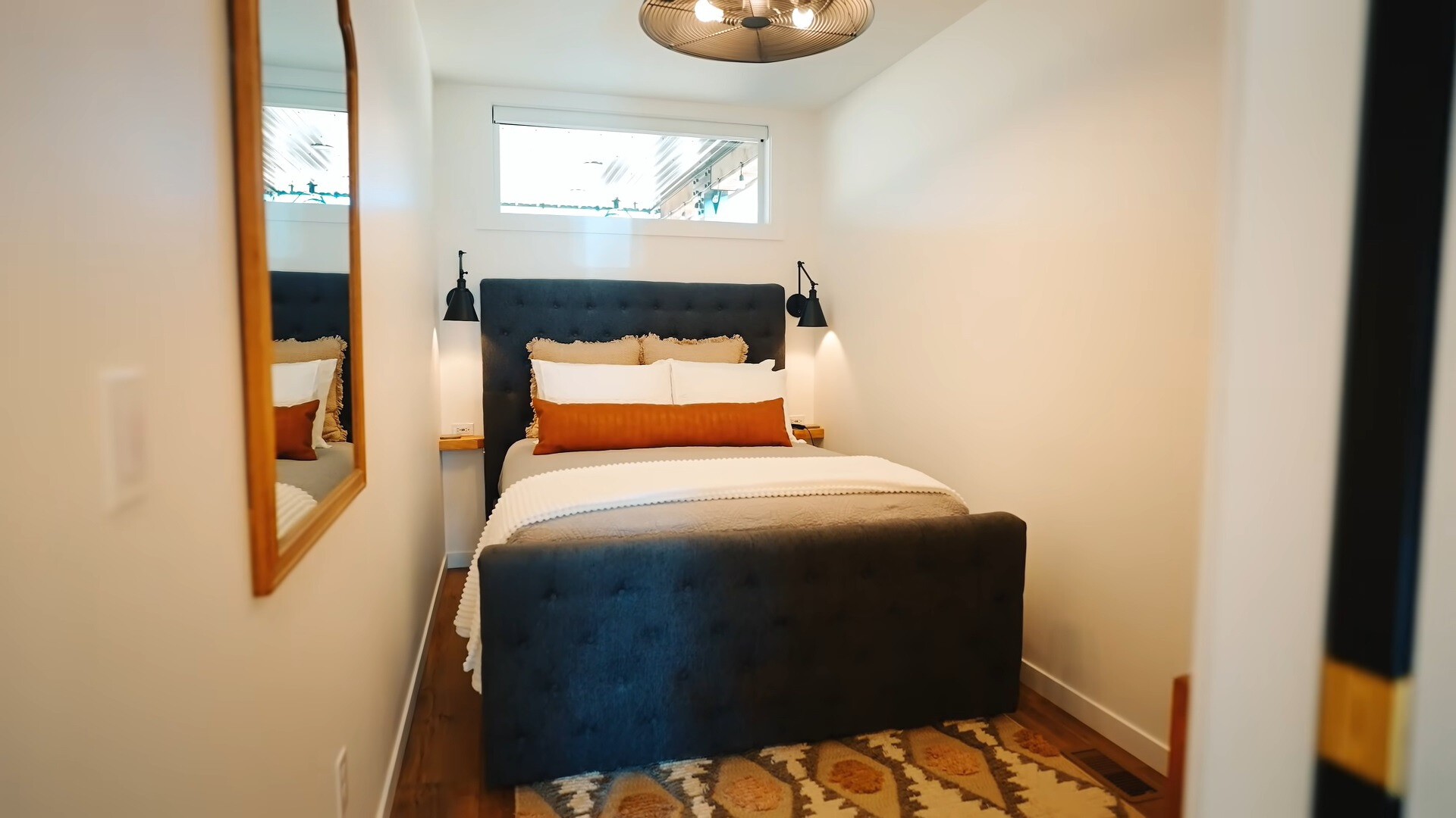 bedroom with a queen sized bed, white walls, lamps on sides of the bed and an overhead lamp