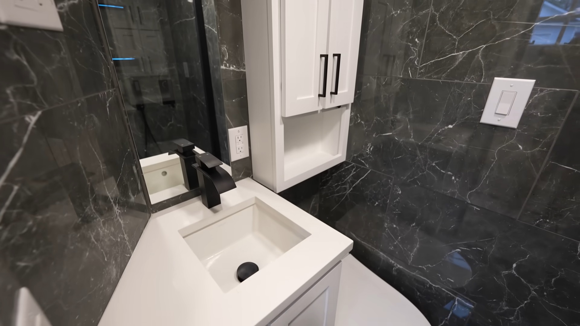 bathroom with black tiles, white cabinet and white sink