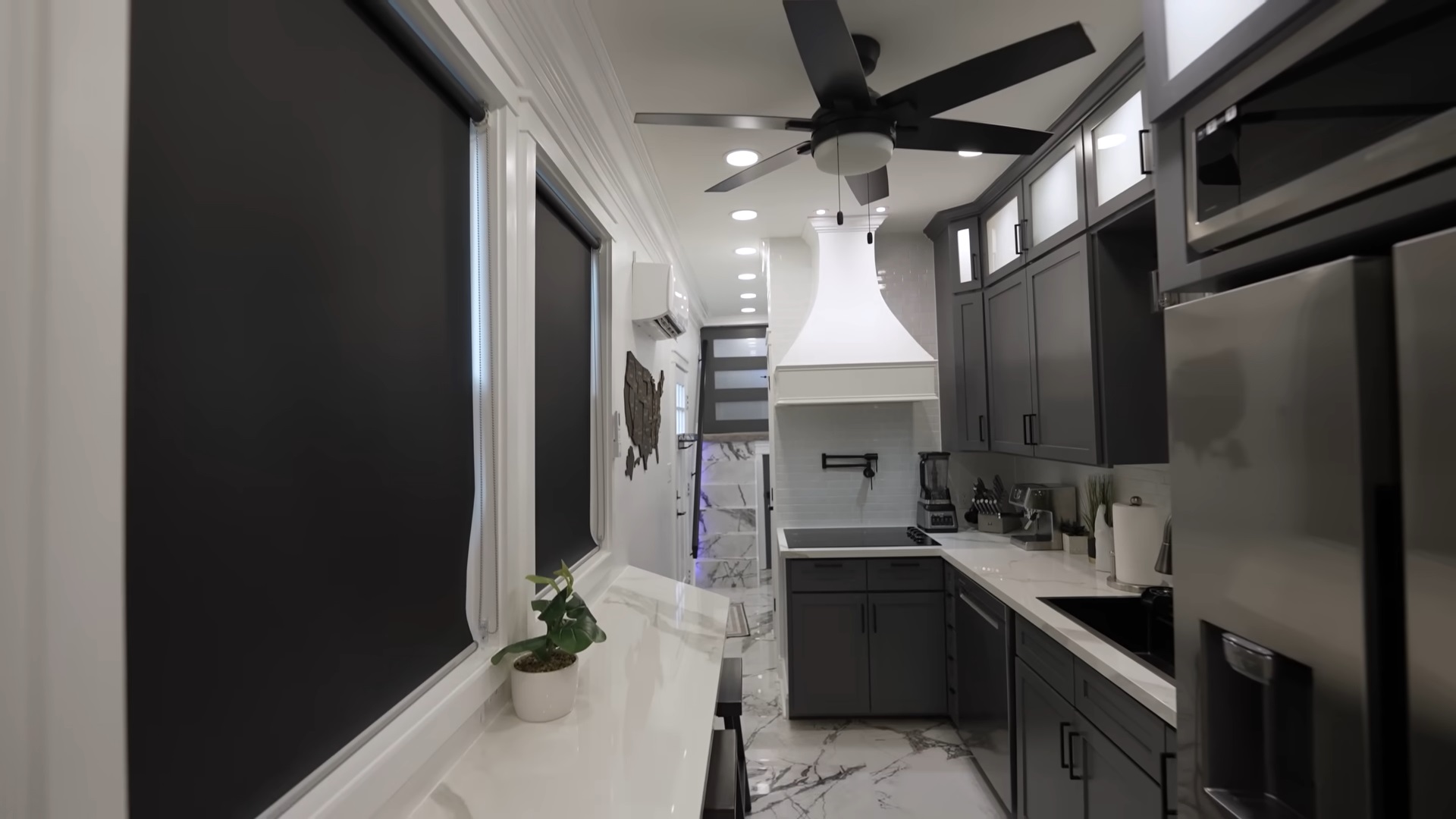 kitchen with two white countertops, black cabinets and big windows