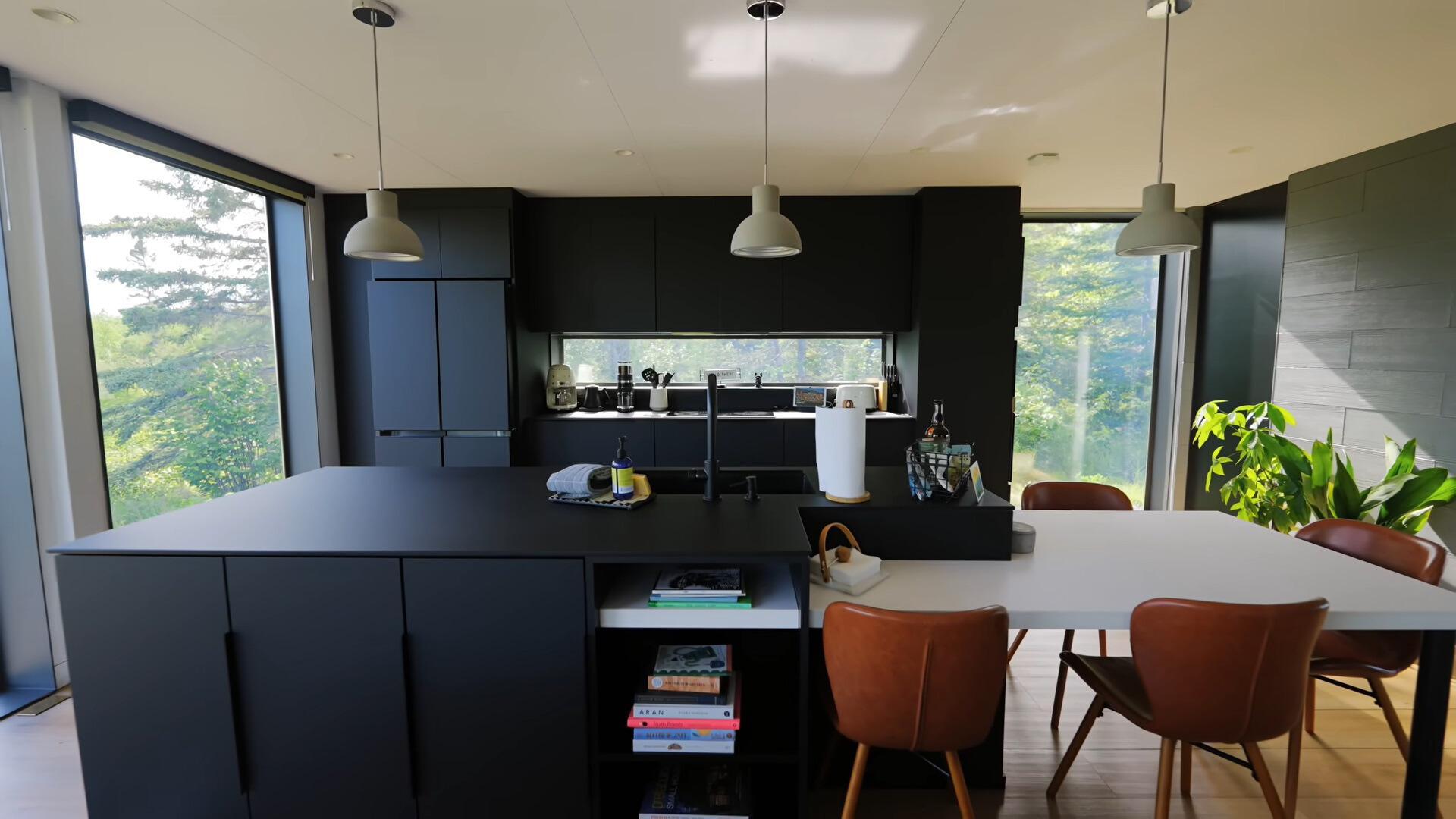 kitchen with black cabinets, big black countertop, white dining table and brown chair and floor to ceiling windows