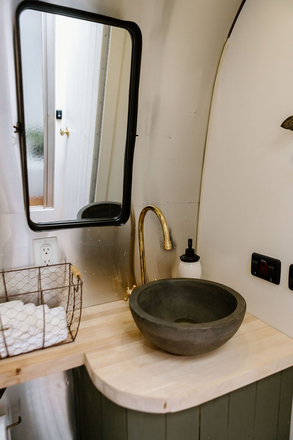 toilet with a black sink, mirror and a gold faucet