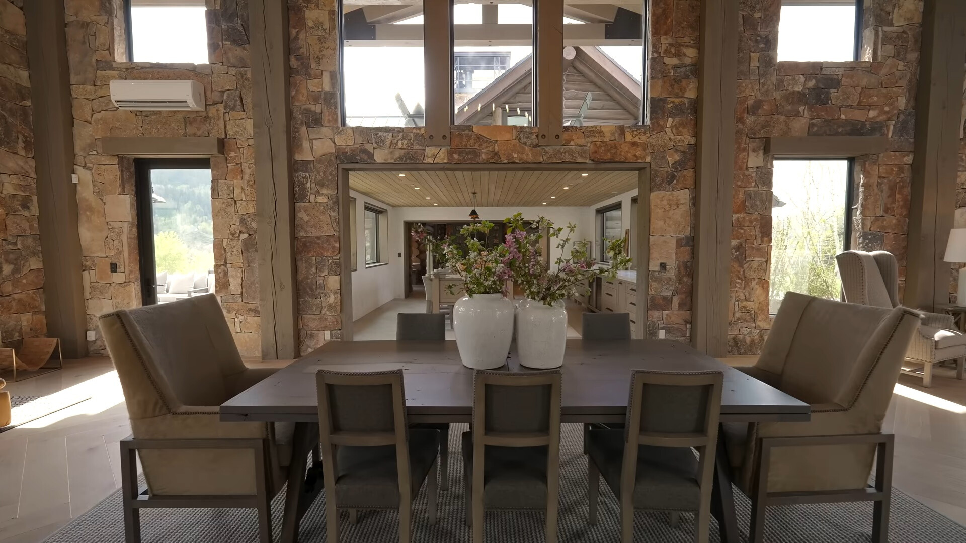 brown dining table surrounded by brown chairs and many windows