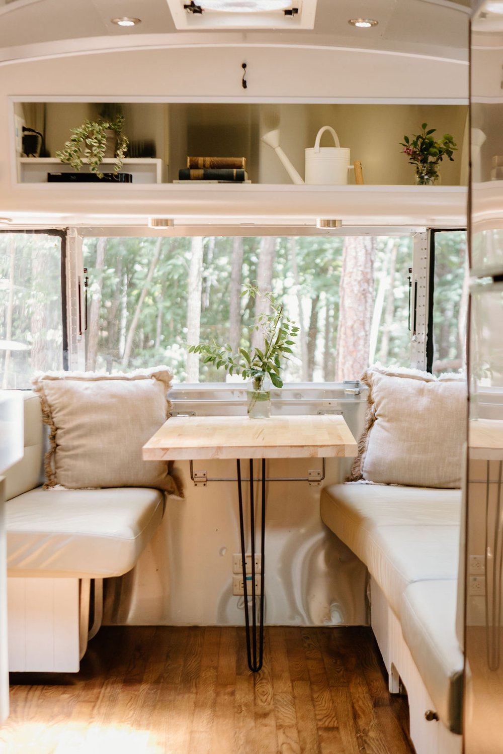 cushioned built-in sitting area with a brown table, shelf above it and windows all around