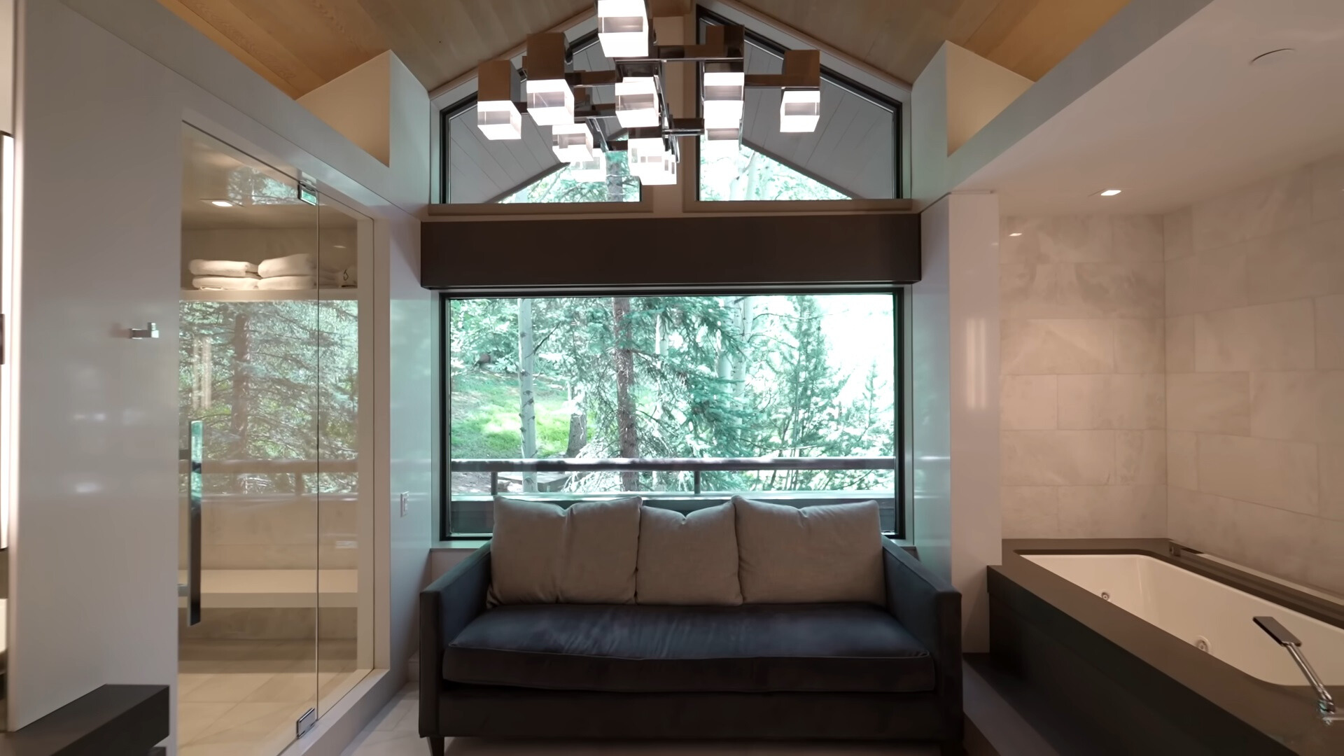 bathroom with a couch, a white bath tub and a glass shower with a sitting area