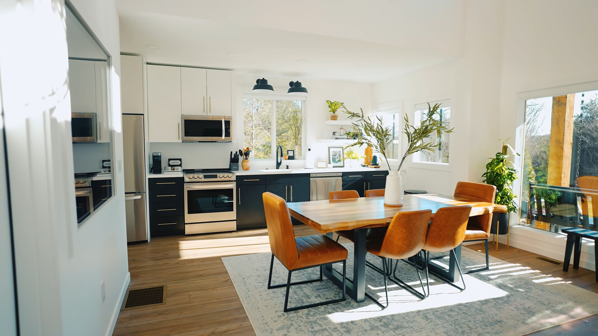 kitchen with black and white cabinets and dining table with a brown, wooden table and orange chairs and big windows