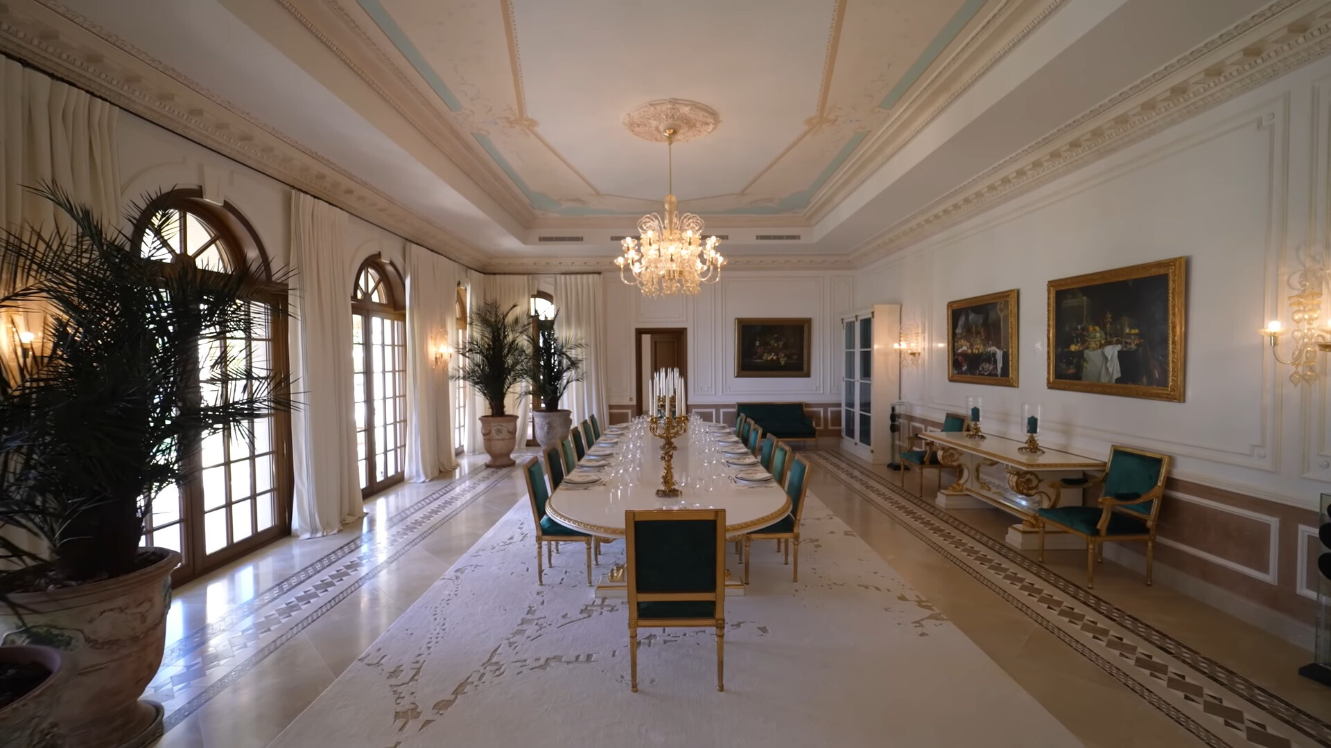 dining room with a long white oval dining table and chairs around it and art pieces on the right wall