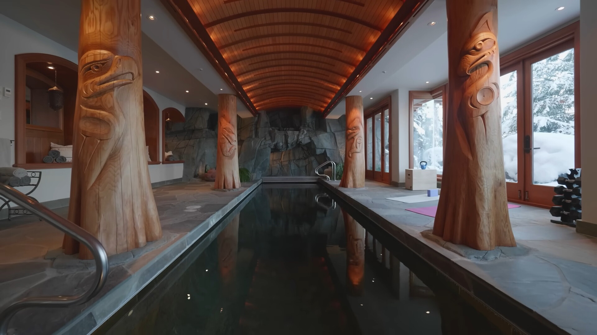 indoor pool with four wooden statues and floor to ceiling windows