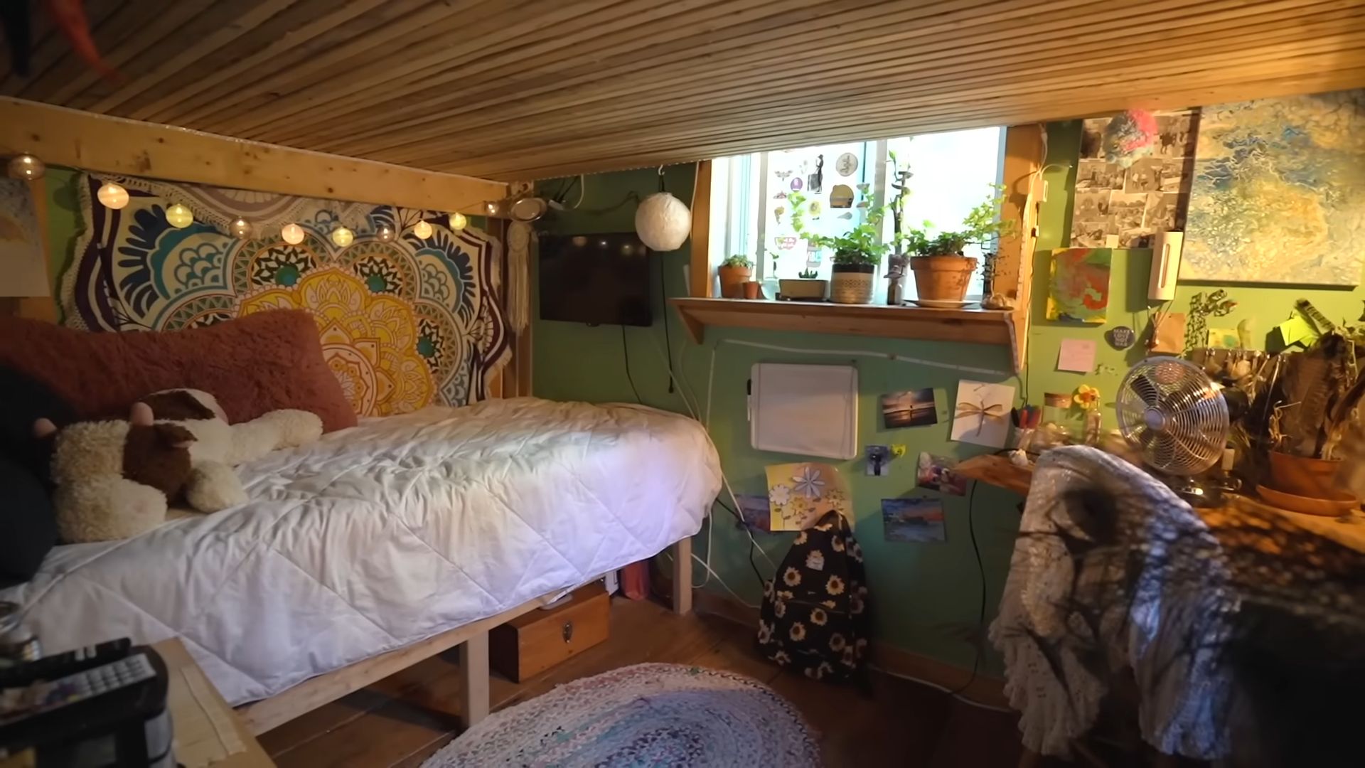 kids bedroom in bright colors, some clutter, bed with plush toys and string lights above it