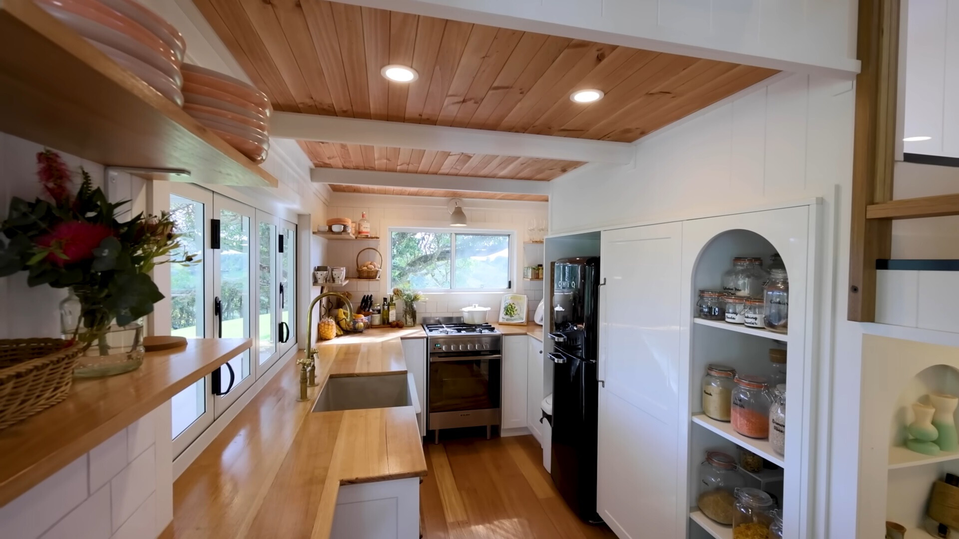 kitchen with brown countertop, big windows, shelf pantry with an arched design