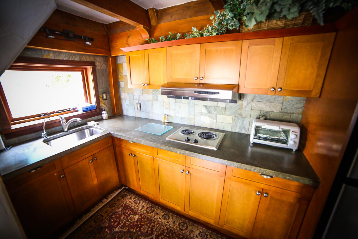 kitchen with a patterned carpet, brown cabinets and a gray countertop and a window