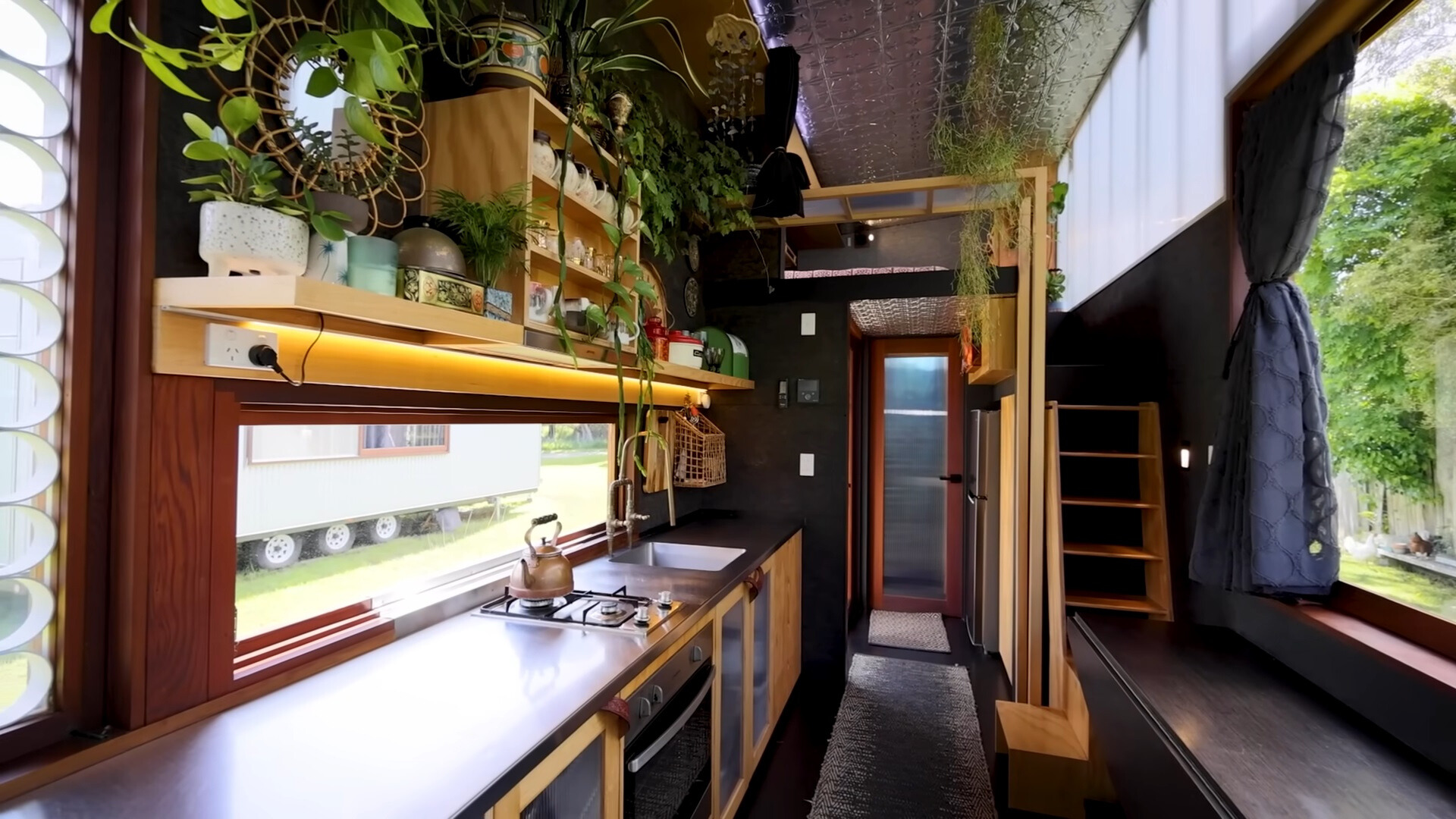 kitchen with a brown countertop, windows on both sides, plants on brown shelves