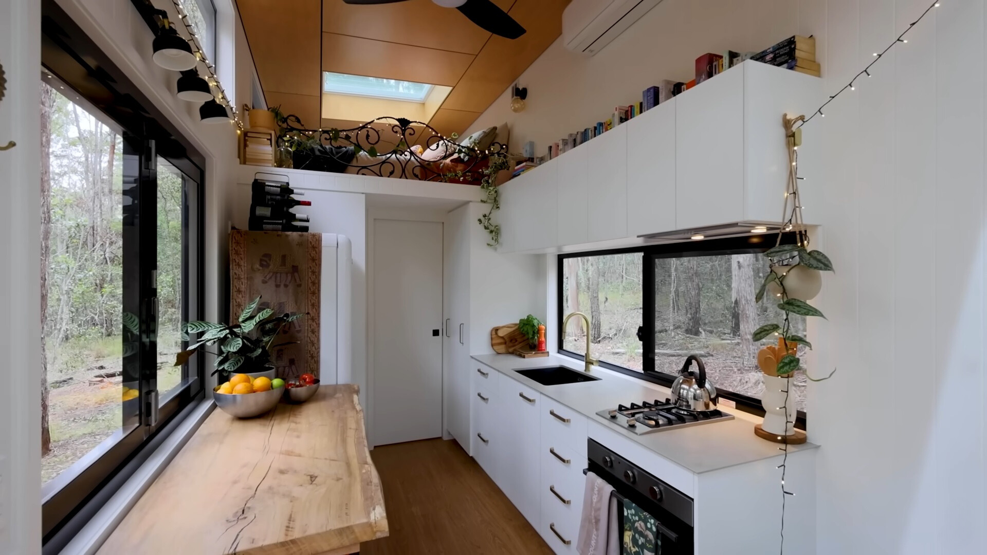 kitchen with a white and wooden countertops, white cabinets with books on top of it and fairy lights