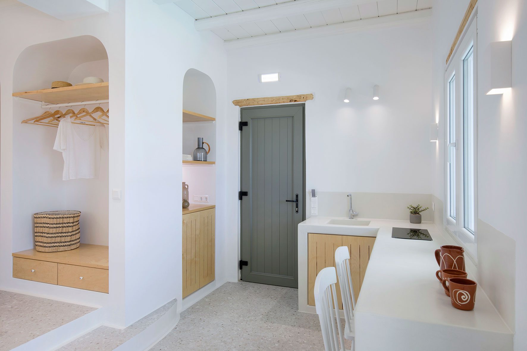 kitchen with an l shaped white countertop and window above it and to white chairs