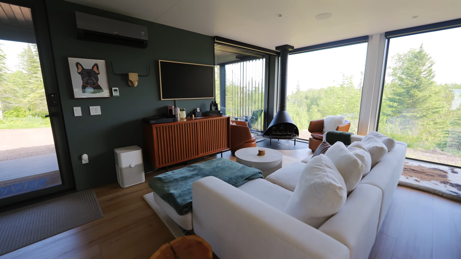 living room with a white couch, brown cabinet, flat screen tv, white round table and floor to ceiling windows