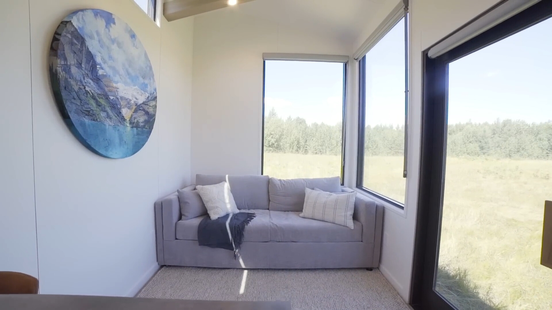 living room with a gray couch and a round art work and very big windows