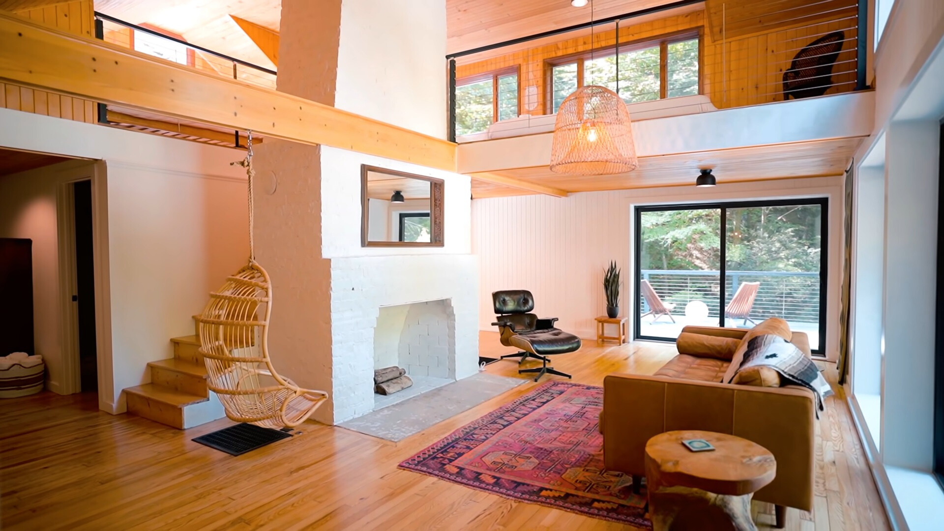 living room with a brown couch, black leather chair and a hanging chair