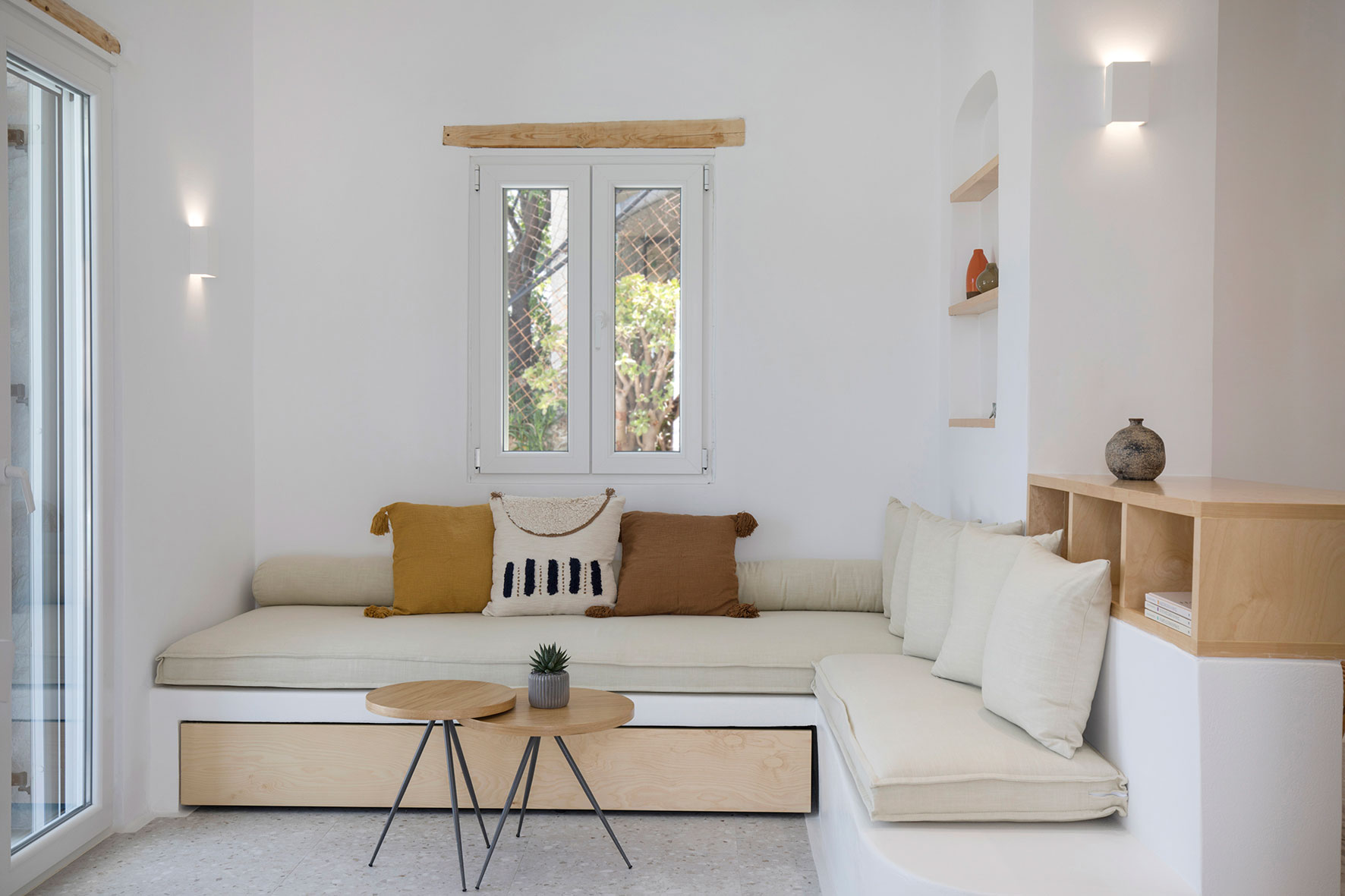 living room with a built in sitting area and beige cushions and round brown tables