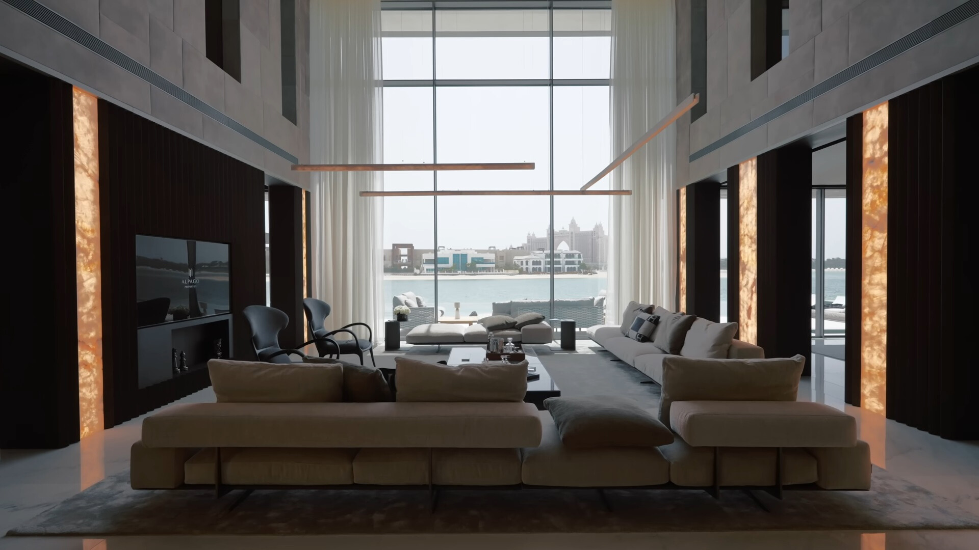 living room with a big white couch, high ceiling, floor to ceiling window and a flat screen tv