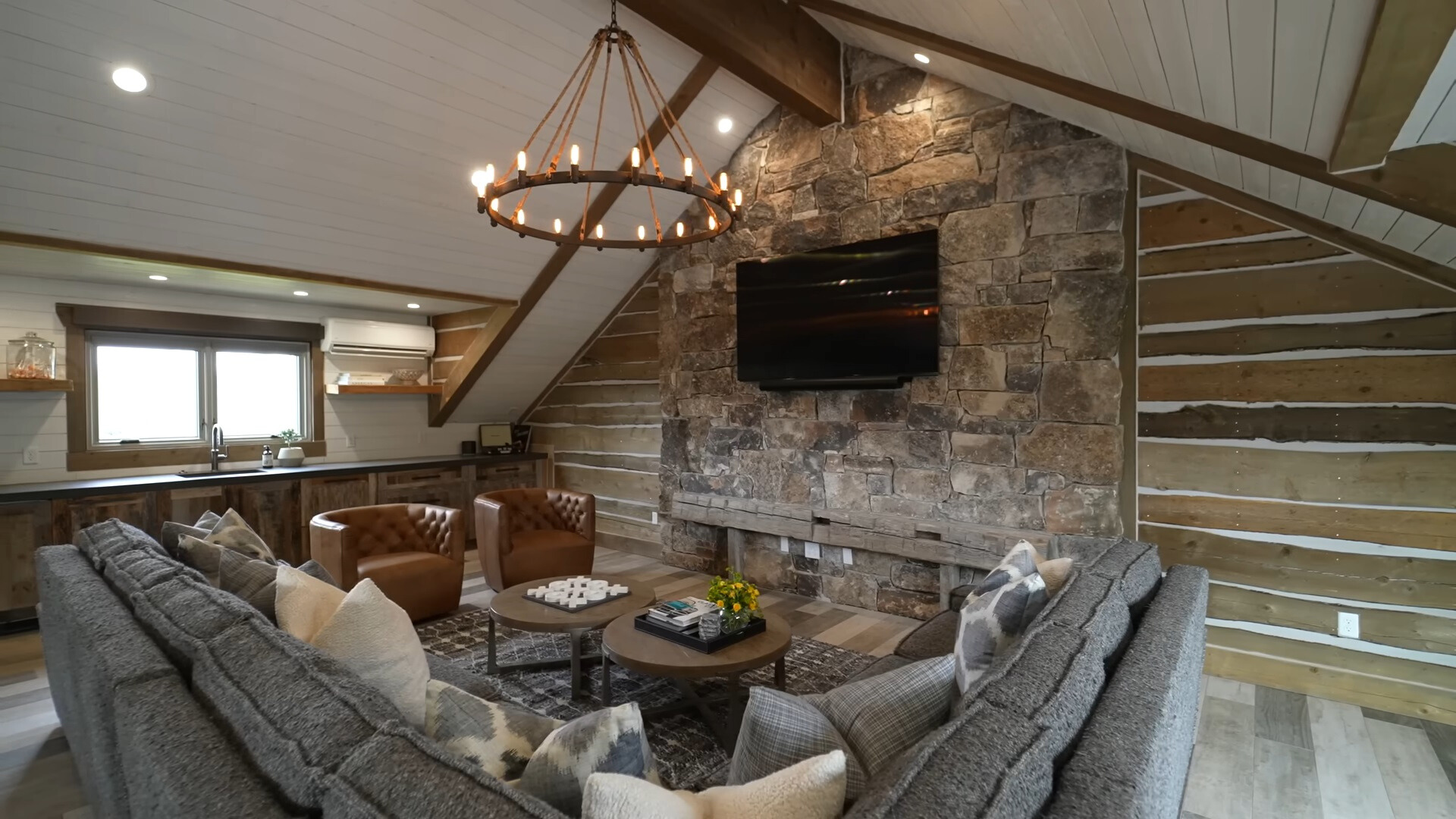 living room with a gray l-shaped couch and leather sofas and a flat screen tv