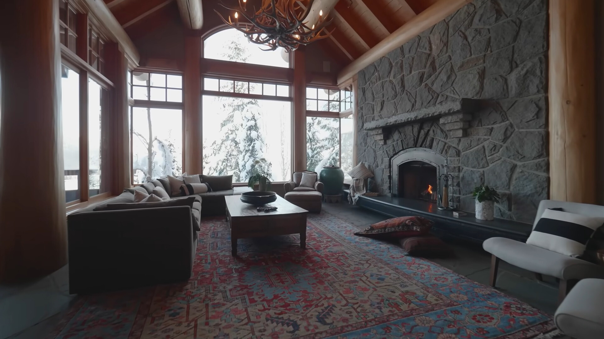 living room with a textured carpet, l-shaped couch, fireplace, floor to ceiling window, wooden desk