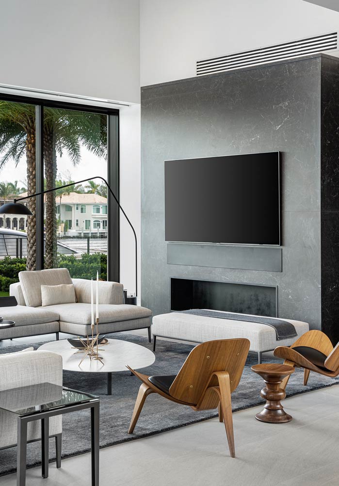 living room with a floor to ceiling window, white couch, two modern brown chairs and a flat screen tv