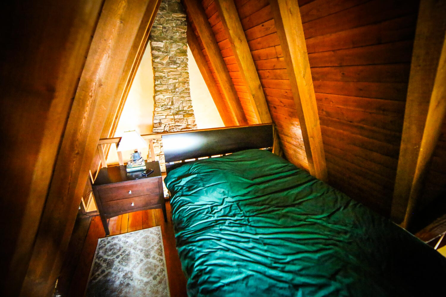 loft bedroom with a queen sized bed and a a wooden bedside table