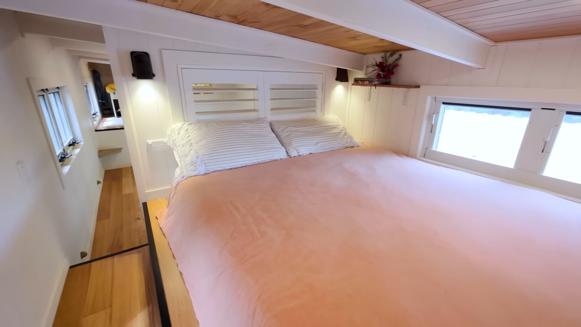 loft bedroom with a big bed, pink bed sheets and windows