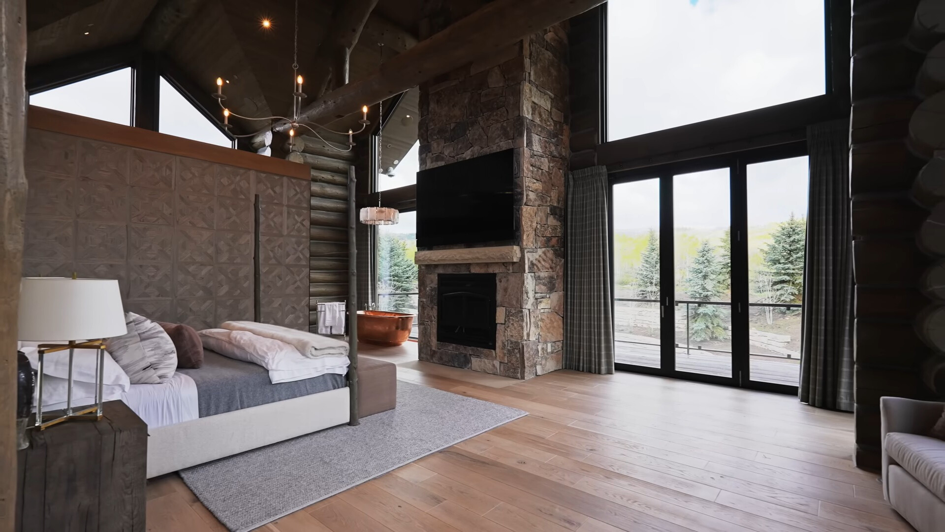 main bedroom with a floor to ceiling window, flat screen tv and a fireplace