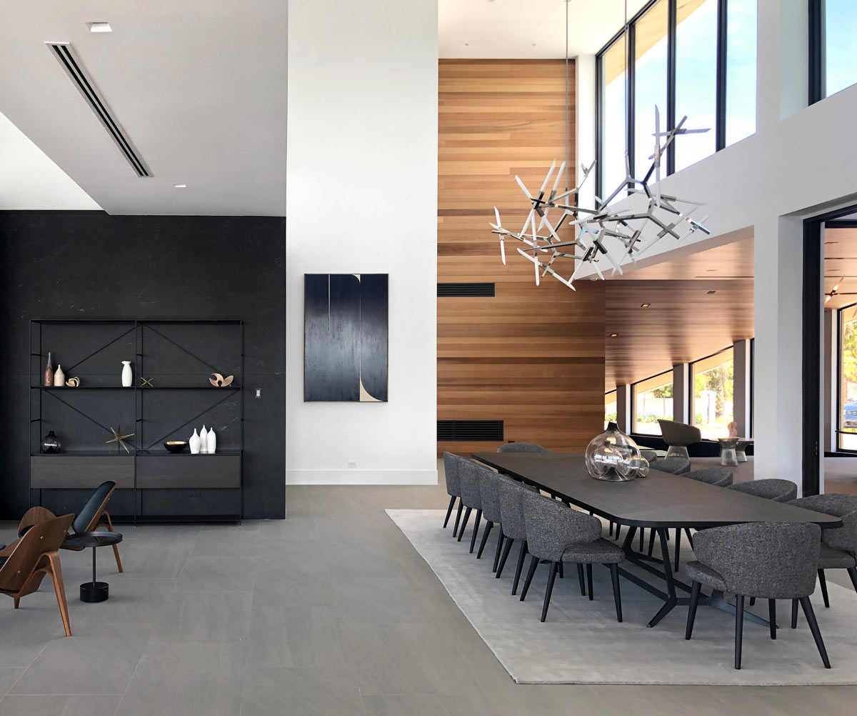 black dining table with gray chairs and a modern chandelier above it