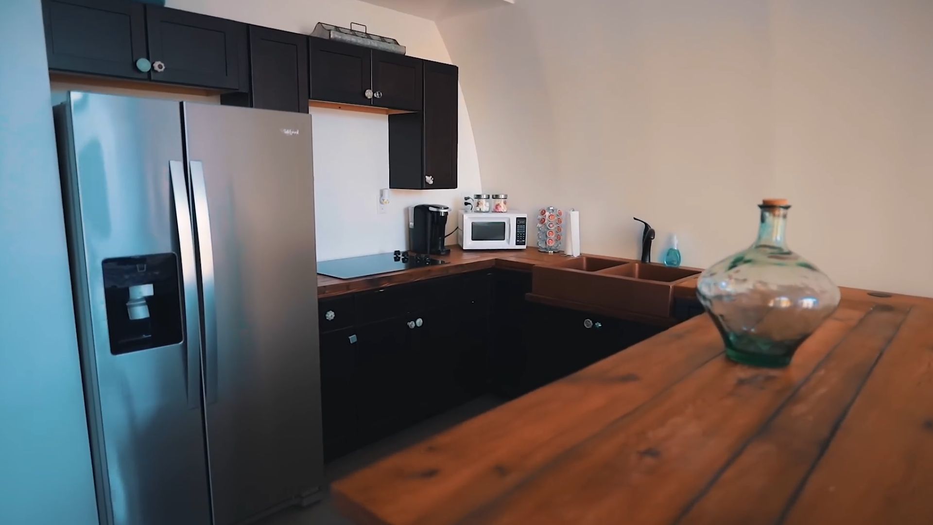 modern kitchen with black cabinets, dark wood countertops, and a double fridge