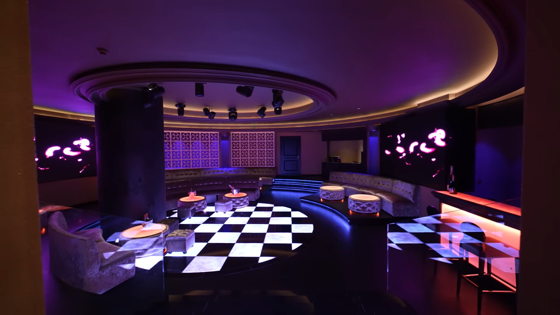 nightclub with black and white tiled dance floor, led lights, round tables and couches