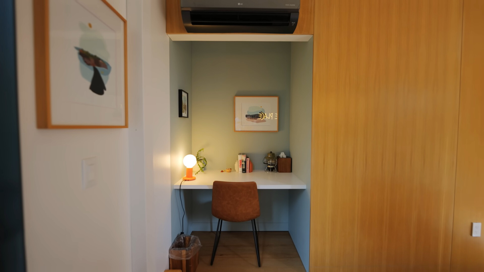 office area of a bedroom with a white desk, brown chair and an ac above