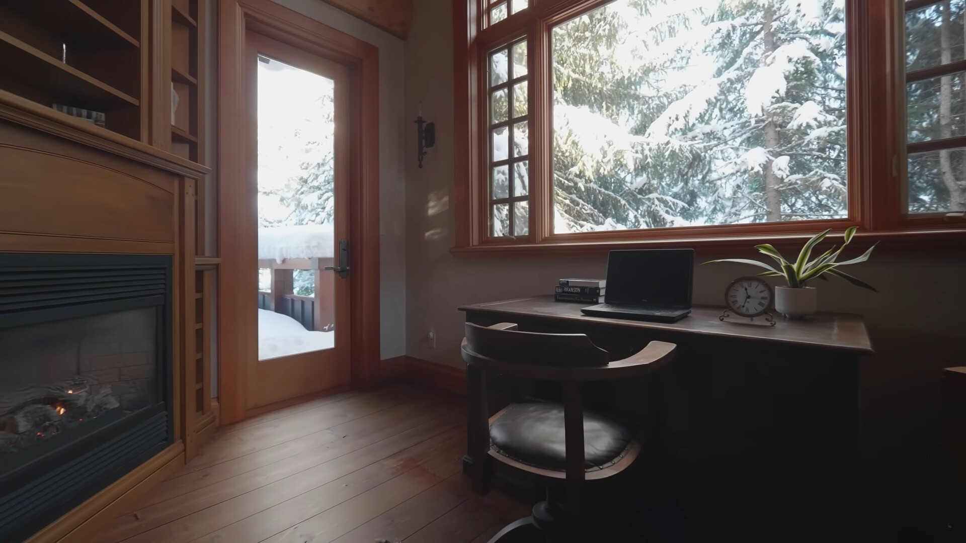 office area with a brown table under the window, brown chair, and a fireplace