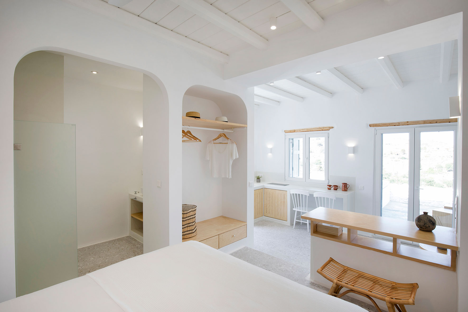 open closet and a wooden bench next to a small shelf, kitchen in the background