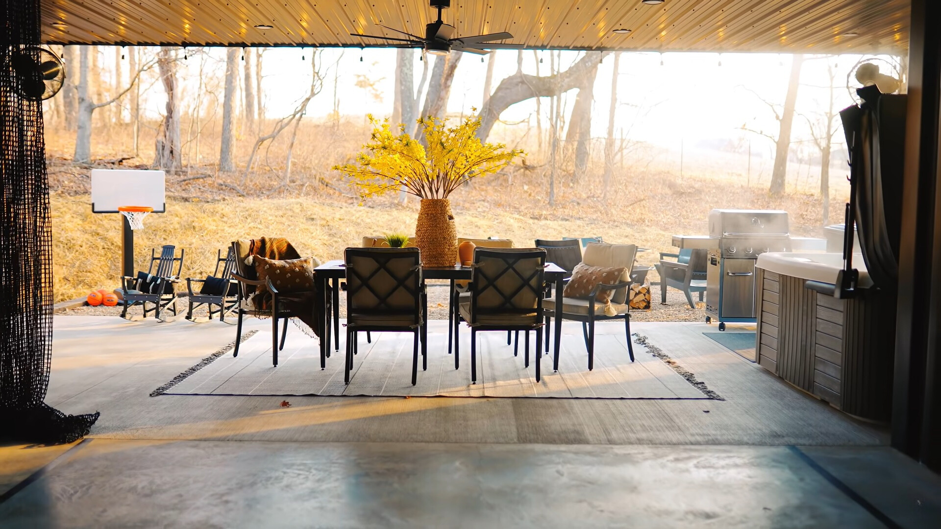 outdoors area of a container house with a hot tub, a dining table, a grill and a child basketball field