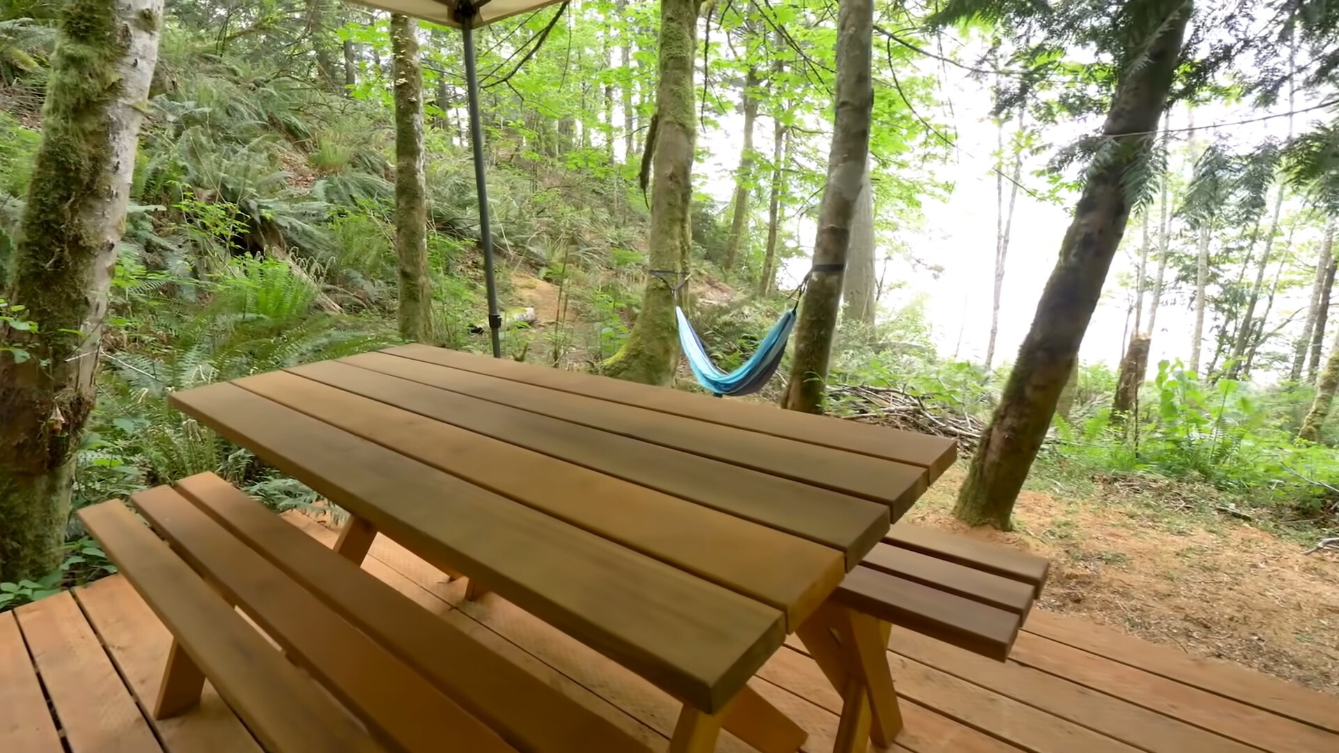 outdoors dining table with benches and a hammock